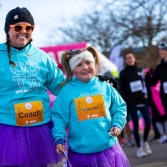 Two smiling Girls on the Run coaches holding participant